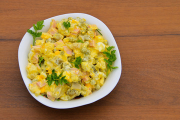 Russian traditional salad olivier on wooden table