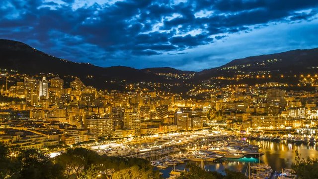 Monaco illuminated by night lights, luxury resort with elite yacht club, aerial