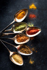 Spices and herbs spoons on a black background
