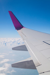 Airplane wing with clouds and sky background