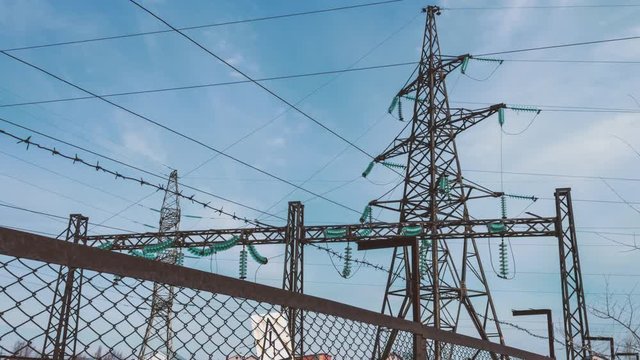 High-voltage power pylons behind the substation fence. Fence of the electrical substation. Energy industry. Renewable clean energy. Transportation of electricity to cities.