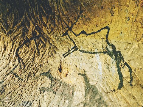 Caveman symbols on sandstone wall. Paint of human hunting,  prehistoric picture.