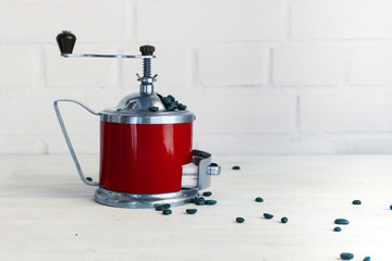 Mechanical coffee mill with coffee beans on white wooden table. Copy space.
