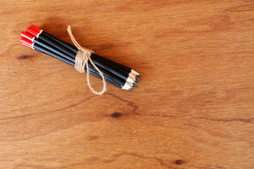 Black pencils tied with a rope of straw yarn. Against the backdrop of plywood wood pattern.

