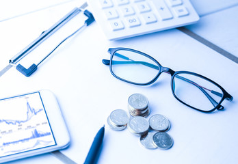glasses, COINS, calculator and mobile phone with K line graph on table,business, finacial ,investment  concept