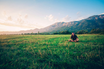 Fototapeta na wymiar Beautiful view of grass field and Himalayan mountains in sunrise. The guy is sitting on the green grass