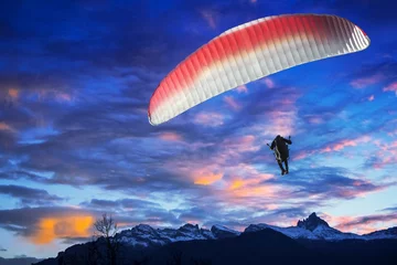 Papier Peint photo Lavable Sports aériens Parapente survolant les montagnes au coucher du soleil d& 39 hiver