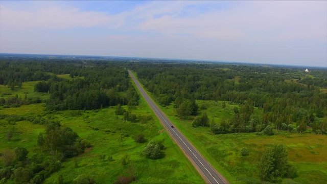 Drone flight over the highway among the green forests