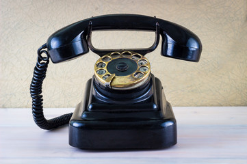 Vintage black phone on wooden table background