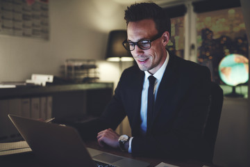 Smiling businessman working on laptop at night