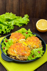 Juicy meat cutlet, baked with grated potatoes and cheese on a cast-iron frying pan on a dark wooden background. Vertical view