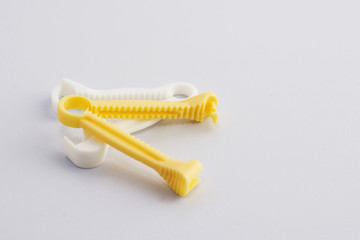 Yellow and White umbilical cord clamp used to clamp off the umbilical cord after a baby's birth.