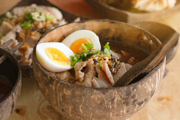 Low key of image of Meat Noodle with egg in a bowler bowl on wooden background. Thai Noodle small line with pork and meat ball. Favorite meal for lunch. Thailand food.