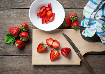 Fresh strawberries, sliced, knife.