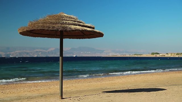 Tropical resort in Tala Bay, Hashemite Kingdom of Jordan. Red sea, gulf of Aqaba. Umbrella on the beautiful beach. View on Israel and Egypt on the other coast