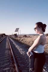 Fototapeta na wymiar Joven con gafas de sol caminando por las vías del tren