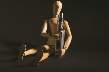 wooden figure holding an electronic cigarette.
