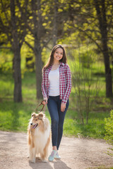 Naklejka na ściany i meble young beautiful woman with long hair walking with collie dog. Outdoors in the park.