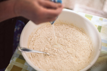 Grandmother pouring milk into pancake batter