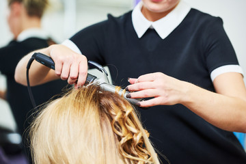 Naklejka premium hairdo in beauty salon. hairdresser making coiffure with curl to wonam