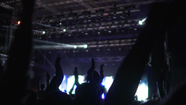 Crowd actively greeting new music band on stage, waving hands, extra slowmotion