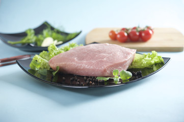 Raw pork on black lettuce and lettuce, portion, schnitzel, cutlet 