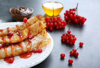 Delicious pancakes with viburnum and sugar powder on white plate