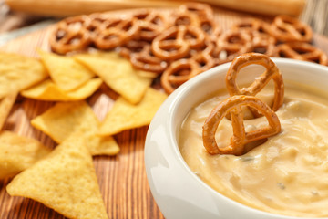 Bowl with beer cheese dip and pretzels on wooden stand