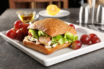 Plate with chicken salad in burger bun on table
