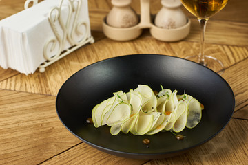 Ceviche of whitefish on served black plate on wooden table