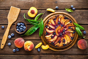 Peach cheese cake or pie with fresh blueberry on wooden rustic background, top view, closeup