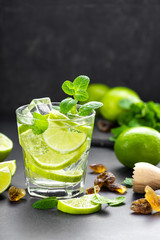 Summer mint lime refreshing cocktail mojito with rum and ice in glass on black background