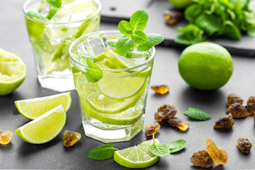 Summer mint lime refreshing cocktail mojito with rum and ice in glass on black background