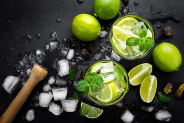  Verfrissende muntcocktailmojito met rum en limoen, koud drankje of drankje met ijs op zwarte achtergrond, bovenaanzicht © Sea Wave