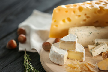 Wooden board with variety of cheese on table