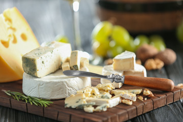 Wooden board with variety of cheese on table