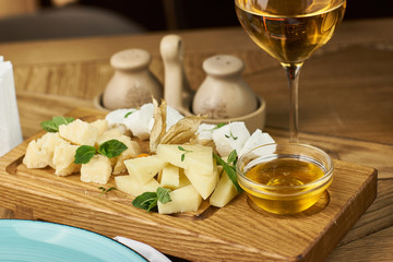 Cheese plate with mozarella, parmesan, honey and glass of white wine.