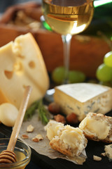 Wooden board with variety of cheese on table