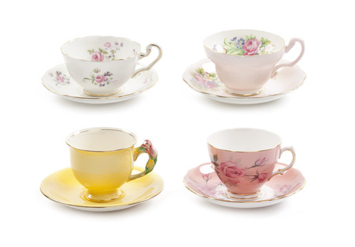 High resolution close-up of four beautiful antique tea cups with saucers isolated on a white background.