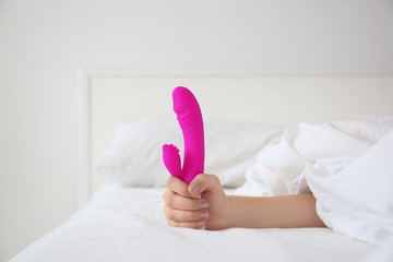 Woman holding dildo in bed