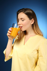 Beautiful woman drinking fresh juice on color background