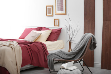 Comfortable bed with burgundy bedding in modern interior design