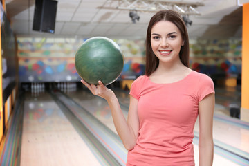 Naklejka premium Young woman with ball in bowling club
