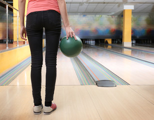 Young woman with ball in bowling club