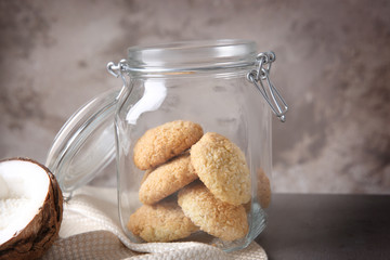 Jar with delicious coconut cookies and napkin on table