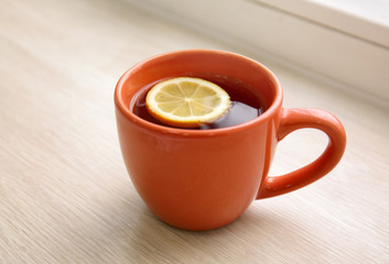 Cup of hot tea with lemon on window sill