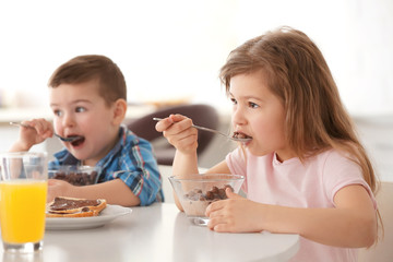 Cute little children having breakfast at home