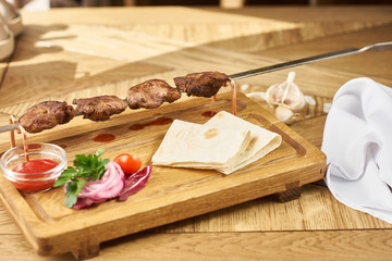 barbecue meat with fresh vegetables, ketchup sauce and bread on wooden board