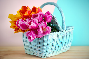 Basket with beautiful bouquet of spring flowers on wooden table