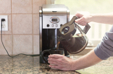 Pouring morning coffee with bright morning light from window